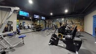 Located at 30–54 Trumbull Street in Hartford, Connecticut, this fitness center is a purpose-built, single-floor facility designed to support a comprehensive workout experience. The space is finished with durable speckled rubber flooring throughout, providing both safety and functionality underfoot. A dark-painted ceiling with exposed ductwork and recessed spotlighting creates an energetic, modern atmosphere while ensuring the area remains well-illuminated during use.

The facility is outfitted with a diverse selection of Spectra and Hoist branded cardio and strength machines, including stationary bikes, ellipticals, cable systems, and multi-function weight machines. Adjustable blue padded benches are centrally positioned, offering versatility for a range of exercises. A dedicated dumbbell rack lines one wall, complemented by full-length mirrors that enhance the sense of space and allow users to monitor their form. Wall-mounted medicine balls in assorted sizes add additional training options.

A bold motivational mural reading "The Stronger You Are, The Better You Feel" serves as a focal point, reinforcing the facility's commitment to fitness culture. Multiple wall-mounted flat-screen televisions provide entertainment throughout the workout. The layout is thoughtfully organized to allow comfortable movement between equipment zones, making the space functional for both individual and simultaneous use.
