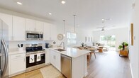 Located at 306 Sugar Mill Dr in New Smyrna Beach, FL, this single-floor, one-bedroom, one-bathroom unit offers a thoughtfully designed layout with a clean, modern aesthetic throughout. Light wood-look flooring flows continuously across every room, tying the interior together with warmth and cohesion.

The open-concept kitchen is a standout feature, equipped with stainless steel appliances — including a French door refrigerator, range, and microwave — set against crisp white shaker cabinetry and light quartz countertops. Pendant lighting and recessed fixtures illuminate the space, while a peninsula counter provides a seamless transition into the adjacent dining area. The dining space is brightened by a large window with views of the outdoors, making it an inviting spot for everyday meals.

The living room is airy and sun-filled, anchored by a sliding glass door that opens directly to a private backyard patio with a lush green lawn — ideal for relaxing or entertaining. A ceiling fan adds comfort to the space.

The bedroom is generously sized, featuring a window that allows ample natural light, a dedicated closet, and direct access to the full bathroom. The bathroom offers a white vanity with ample storage, a glass-enclosed shower, and a window for natural ventilation. The overall atmosphere of this unit is bright, clean, and move-in ready.