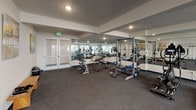 Located at 13637 Leadwell St in the Van Nuys neighborhood of Los Angeles, this single-level fitness facility is thoughtfully designed to support a comprehensive workout experience. The space is organized into distinct functional zones, all connected by durable rubber flooring that provides both safety and comfort underfoot.

The strength training area is outfitted with power racks, barbells, weight plates, and adjustable benches, complemented by a full dumbbell rack. Floor-to-ceiling mirrors line the walls, visually expanding the space and allowing users to monitor their form. Recessed lighting keeps the area well-lit throughout.

A dedicated cardio and functional training zone features a row of stationary spin bikes, a treadmill, and a freestanding heavy bag and speed bag station, making it suitable for diverse training styles. Glass double doors along this section allow natural light to filter in and offer views of an adjacent outdoor area.

A small transitional entry area includes a wooden bench and wall-mounted artwork, providing a welcoming spot to prepare before or unwind after a workout. An accessible restroom is also available on-site, featuring white tile walls, wood-look flooring, grab bars, and ADA-compliant fixtures, ensuring the facility is inclusive and fully equipped for all users.