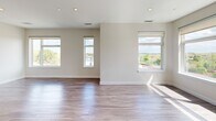 This thoughtfully designed 1-bedroom, 1-bathroom unit in Saugus, MA offers a contemporary living experience across a single floor. The open-concept kitchen and living area serves as the heart of the home, bathed in natural light streaming through multiple large windows that frame scenic views of the surrounding neighborhood and lush treetops. Recessed lighting throughout enhances the bright, airy ambiance. The kitchen is outfitted with stainless steel appliances, including a gas range, microwave, dishwasher, and French door refrigerator. Sleek two-tone cabinetry — white upper cabinets paired with dark wood lower cabinets — is complemented by crisp white countertops and a white tile backsplash. A central island provides additional counter space and casual seating. Hardwood-style flooring flows seamlessly through the living areas and bedroom, adding warmth to the modern aesthetic. The bedroom is generously proportioned with a large window offering expansive outdoor views and ample wall space. The bathroom features a wide vanity with a white countertop, modern cabinetry, and large-format light tile flooring, conveying a clean and polished finish. A hallway connects the spaces efficiently, completing this well-appointed, move-in-ready unit.
