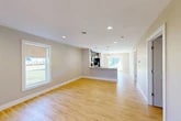 Located at 100 Pheasant's Run in Clinton, NY, this well-designed single-floor home offers 2 bedrooms and 2 bathrooms within a thoughtfully laid-out floor plan. The open-concept living and kitchen area serves as the heart of the home, featuring warm light wood flooring, recessed lighting, and large windows that invite abundant natural light and outdoor views. The kitchen is appointed with rich dark wood cabinetry, granite countertops, stainless steel appliances including a refrigerator, range, microwave, and dishwasher, and pendant lighting above the island — a functional and attractive space for cooking and entertaining. Both bedrooms are comfortably sized with the same warm wood flooring, neutral wall tones, and natural light; the second bedroom benefits from a large window overlooking the surrounding greenery. The bathrooms are finished with granite-top vanities and clean, modern fixtures, including a walk-in shower in one bath. A dedicated laundry room houses a full-size washer and dryer with a utility shelf. The home also includes an attached garage with an automatic opener, five closets for ample storage, and a welcoming entryway. The overall aesthetic is clean, modern, and move-in ready.