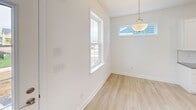 This two-story home in Lewes, Delaware offers a well-designed layout across two floors. The main level features an open-concept kitchen and dining area bathed in natural light from multiple windows. The kitchen is appointed with crisp white shaker cabinets, a central island with a dark countertop, stainless steel appliances including a range, microwave, and refrigerator, plus a pantry for added storage. Recessed lighting and light-toned luxury vinyl plank flooring carry throughout, creating a clean, cohesive aesthetic. The dining area includes a pendant light fixture and windows that bring in additional natural light. Sliding glass doors lead to a private balcony with views of the surrounding neighborhood. Upstairs, the spacious primary bedroom features a ceiling fan, a walk-in closet, and an en-suite bathroom complete with a granite-topped vanity, a window for natural light, and direct access to a walk-in closet. The second bedroom also includes a ceiling fan and a built-in closet with bi-fold doors. The second full bathroom offers a granite vanity, tile flooring, and a tub-shower combination. Both floors are connected by a staircase, and the home's bright, neutral palette creates a welcoming and move-in-ready atmosphere throughout.