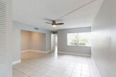 Located at 5671 Washington St in Hollywood, FL, this one-bedroom, one-bathroom residence offers a clean, functional layout spread across a single floor. Light-toned ceramic tile flooring runs consistently throughout every room, lending a cohesive and easy-to-maintain aesthetic to the entire space.

The living room is a bright, open area featuring a ceiling fan with light fixture and a large window dressed with vertical blinds that invites generous natural light and views of lush greenery outside. The space flows naturally into a separate dining area, which benefits from its own track lighting and connects conveniently to the kitchen.

The galley-style kitchen is well-appointed with white upper cabinetry, warm wood-toned lower cabinets, light quartz countertops, a double-basin sink, and white appliances including a range, microwave, and dishwasher — offering efficient use of space.

The bedroom is a generously sized retreat with its own ceiling fan, a closet, and access to additional storage. The unit features an impressive five closets in total, providing exceptional storage throughout.

The bathroom is clean and modern, showcasing a wood-toned vanity with a quartz countertop, a tiled shower-tub combination with a curved curtain rod, and chrome fixtures. The space is finished with soft gray walls and white trim throughout, creating a calm, neutral ambiance.