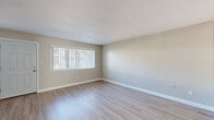 Located in National City, CA, this well-appointed 2-bedroom, 1-bathroom residence offers a practical and comfortable single-floor layout. The combined kitchen and living area serves as the heart of the home, with the kitchen featuring white cabinetry with brushed nickel hardware, light quartz-style countertops, black appliances including a gas range and refrigerator, and a stainless steel sink — all set atop durable wood-look flooring. The living room is bathed in natural light through large windows with vertical blinds, complemented by neutral gray-toned walls and the same warm hardwood-style flooring, creating a clean and inviting atmosphere. Both bedrooms are finished with plush carpeting and feature mirrored sliding closet doors that add depth and storage functionality. Natural light filters in through blinds-covered windows in each room. A hallway connects the bedrooms to the shared bathroom, which is outfitted with a white vanity with a marble-style countertop, a square-framed mirror, and a full tub-shower combination with white tile surround. Neutral tones, clean lines, and consistent finishes throughout the space create a cohesive, move-in-ready environment ideal for everyday living.
