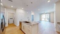 Located at 3500 Cox Rd in Henrico, VA, this thoughtfully designed 2-bedroom, 2-bathroom residence offers a bright and modern living experience across a single, well-planned floor. Light hardwood flooring flows seamlessly throughout, unifying each space with warmth and consistency.

The open-concept kitchen is a standout feature, anchored by a generous center island topped with striking granite countertops and an undermount sink illuminated by elegant pendant lighting. White shaker cabinetry, a classic tile backsplash, and a full suite of stainless steel appliances — including a French door refrigerator, range, and built-in microwave — complete this polished culinary space.

The kitchen opens directly into the living room, which is finished with crown molding, a ceiling fan, and a sliding glass door that leads to a private balcony overlooking the surrounding community. Natural light pours in, creating an airy, welcoming ambiance.

Both bedrooms are comfortable and well-lit, with large windows that invite natural light. The primary bedroom offers a generous footprint with dedicated closet space. The bathrooms feature clean white cabinetry, quartz countertops, and modern fixtures. A dedicated in-unit laundry room with full-size washer and dryer adds everyday convenience to this move-in-ready home.