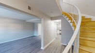 Located at 3308 Wickslow Rd in Wilmington, NC, this two-story home presents a clean, modern aesthetic defined by neutral tones, light hardwood-style flooring, and crisp white trim throughout. The main level opens to a spacious living area with an open layout, where a curved staircase with warm wood treads and white railings serves as a distinctive architectural focal point. An adjacent lower-level living space, accessible through an open archway, adds functional versatility to the floor plan.

The kitchen is outfitted with white shaker-style cabinetry, granite countertops, a white subway tile backsplash, and stainless steel appliances including a range and over-the-range microwave. A separate room on the main level features sliding glass doors that open directly to a private outdoor patio, providing a seamless indoor-outdoor connection.

The bathrooms feature granite-topped vanities with white cabinetry and tub-shower combinations with clean white surrounds. A combined laundry area with a full-size washer and dryer adds practical convenience. The bedrooms are well-proportioned, each equipped with ceiling fans and ample natural light from windows with blinds. The overall interior presents a well-maintained, move-in ready environment.