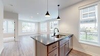Located at 80 S. Sounders Ave in Columbus, OH, this well-appointed one-bedroom, one-bathroom residence offers a thoughtfully designed single-floor layout with a clean, contemporary aesthetic throughout. Light wood-look flooring flows seamlessly through the open-concept living, dining, and kitchen area, creating a cohesive and inviting atmosphere filled with natural light from multiple large windows fitted with blinds.

The kitchen is a standout feature, centered around a substantial island with dark granite countertops and an undermount sink, illuminated by stylish black pendant lights. Warm-toned cabinetry, a classic subway tile backsplash, and a full suite of stainless steel appliances — including a French door refrigerator, range, microwave, and dishwasher — complete this functional and attractive space.

The living area is bright and open, benefiting from expansive windows that frame views of the surrounding greenery. A private patio with a cable-rail balcony overlooks a beautifully landscaped courtyard with lush plantings and seating areas.

The bedroom offers plush carpeting, natural light, and access to a dedicated closet. The bathroom features a walk-in shower with white subway tile walls and matte black fixtures. A dedicated laundry area adds everyday convenience to this polished, move-in-ready home.