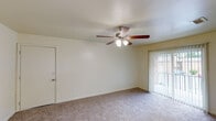 This single-floor residence offers a well-organized layout with a clean, functional design throughout. The living area is finished with wall-to-wall carpet and features a ceiling fan with integrated lighting, providing comfort year-round. A sliding glass door fitted with vertical blinds opens to an outdoor area, allowing natural light to fill the room. Adjacent to the living space, the dining area transitions to rich hardwood-style flooring and is illuminated by an elegant multi-bulb chandelier, with a window dressed in horizontal blinds adding to the natural brightness of the space. Multiple bedrooms continue the carpeted flooring and each include ceiling fans with light fixtures, along with windows that invite natural light and outdoor views. The bathrooms are finished with warm earth-toned tile surrounds on the tub and shower combinations, complemented by wood-style flooring, white vanities, and mirrors. A hallway connects the bedrooms and bathrooms, offering convenient access and additional closet storage. Throughout the unit, neutral cream-toned walls provide a versatile backdrop, and consistent design elements lend the space a cohesive, understated character.