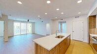 Located at 2058 East Apache Boulevard in Tempe, Arizona, this single-floor residence offers four bedrooms and two bathrooms within a well-designed, modern layout. Light wood-tone flooring runs throughout the space, lending warmth and visual continuity across every room.

The kitchen serves as a central hub, anchored by a large island with a white quartz countertop, an undermount sink, and warm wood cabinetry. Two-tone upper and lower cabinets are paired with stainless steel appliances, including a range, microwave, and French door refrigerator, complemented by a clean white tile backsplash and recessed lighting overhead.

The open living area is bright and airy, with a ceiling fan and floor-to-ceiling sliding glass doors that lead to a private balcony, offering views of the surrounding exterior. Natural light fills the space generously through the expansive glazing.

The spacious primary bedroom features sliding glass door access and a generous walk-in closet with built-in shelving and hanging rods. A second walk-in closet provides additional storage. The secondary bedrooms are well-proportioned, each with windows that invite natural light and outdoor views, and ceiling fans for comfort.

Both bathrooms are finished with wood-tone vanity cabinetry, white quartz countertops, and shower-tub combinations with clean white tile surrounds, maintaining the space's consistently modern, neutral aesthetic.