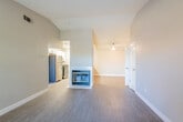 This single-story residence offers a thoughtfully designed layout with a warm, neutral color palette throughout. The open living area is a standout feature, boasting vaulted ceilings that lend a sense of spaciousness and airiness to the space. Dark hardwood-style flooring runs throughout the main areas, providing a sleek, modern contrast to the light-toned walls. A central peninsula fireplace serves as a focal point, elegantly dividing the living and dining areas while adding a cozy ambiance.

The kitchen is well-appointed with white cabinetry, dark granite-style countertops, stainless steel appliances including a refrigerator and gas range, and a functional peninsula with a built-in sink — ideal for both cooking and casual dining.

The bedrooms are generously proportioned, each featuring the same dark hardwood-style flooring, vaulted or angled ceilings, and windows that invite natural light and views of surrounding greenery. The bathrooms are finished with matching dark countertops, white cabinetry, and full tub-shower combinations with chrome fixtures, maintaining a consistent and clean aesthetic. Overall, the space presents a cohesive, modern, and comfortable living environment.
