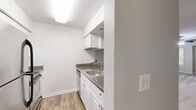 Located at Harbor Pointe in Sandy Springs, GA, this one-bedroom, one-bathroom residence offers a well-organized single-floor layout designed for comfortable everyday living. The open living room is finished with neutral-toned carpet, a textured ceiling, and a ceiling fan, while vertical blinds and a window allow for natural light. The space connects seamlessly to the kitchen via a pass-through counter with a built-in breakfast bar — a practical feature that enhances the open feel between the two areas. The kitchen is efficiently designed with white cabinetry, granite-style countertops, a double-basin sink, a black refrigerator, an electric range, and hardwood-style flooring, providing ample storage and prep space. The bedroom is a comfortable, carpeted room featuring its own window, a ceiling fan, and access to a dedicated walk-in closet equipped with wire shelving. The bathroom includes a full soaking tub and shower combination with tiled accents, a white vanity with granite-style countertops, and hardwood-style flooring. A hallway connects the main living areas, completing the efficient and cohesive floor plan of this Sandy Springs residence.