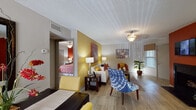 This single-floor residence at 2020 Armstrong Mill Rd in Lexington, Kentucky offers a thoughtfully designed layout highlighted by bold, colorful accent walls and contemporary finishes throughout. The living area welcomes you with warm hardwood-style flooring, vibrant yellow and orange accent walls, and an abundance of natural light filtering through blinds and a front-facing window. The space is generously proportioned, providing ample room for comfortable seating arrangements. The kitchen is a standout feature, showcasing dark espresso cabinetry, granite countertops with a peninsula, stainless steel appliances including a range, microwave, and refrigerator, and a deep double sink — a functional and stylish space for cooking and entertaining. Two well-appointed bedrooms each feature plush carpeting, ceiling fans, sliding closet doors, and bold accent walls in deep red and charcoal tones that lend each room a distinct character. Natural light flows into the bedrooms through large windows dressed with coordinating curtains. The bathrooms are finished with dark vanity cabinetry, granite countertops, large mirrors, and tub/shower combinations, offering a clean and modern aesthetic. Overall, the residence presents a lively, cohesive design with a warm color palette throughout.