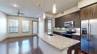 Located in Houston's vibrant EaDo neighborhood, this well-appointed one-bedroom, one-bathroom residence offers a thoughtfully designed single-floor layout. The open-concept kitchen and living area serves as the heart of the home, showcasing rich, dark hardwood floors that flow throughout. The kitchen is outfitted with dark espresso cabinetry, a subway tile backsplash, stainless steel appliances including a French door refrigerator and range, and a granite-topped island with pendant lighting — ideal for both cooking and entertaining. The spacious bedroom features gleaming hardwood floors, multiple windows framing city views, and a ceiling fan for added comfort. The full bathroom is elegantly finished with a granite vanity, dark wood cabinetry, large soaking tub, separate shower, and tile flooring. A generously sized walk-in closet with multiple shelving rods and carpeted flooring offers ample storage. The unit also includes a dedicated laundry area. Throughout the residence, neutral tones, crown molding, and an abundance of natural light create a clean, modern ambiance suited for comfortable urban living.