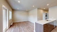 Located at 4040 Hayesville Dr NE in Salem, Oregon, this single-story, three-bedroom, two-bathroom home offers a well-designed layout with modern finishes throughout. The open-concept living and kitchen area serves as the heart of the home, featuring warm-toned luxury vinyl plank flooring, recessed lighting, and a kitchen island with a white countertop. The kitchen is equipped with rich dark wood cabinetry, stainless steel appliances including a refrigerator, range, and over-the-range microwave, making it both functional and visually appealing. Natural light filters in through windows with blinds, complementing the neutral, warm beige wall tones found throughout the home. A wall unit provides climate control in the living area, which also offers direct access to the outdoors. The three bedrooms feature plush carpeting and closets with sliding panel doors, providing ample storage. The primary bedroom is a comfortable size with dedicated closet space. The two bathrooms are clean and practical — one includes a full soaking tub and shower combo with brushed nickel fixtures, while the other features a standalone walk-in shower with sliding glass doors and LVP flooring. A connecting hallway ties the layout together efficiently.