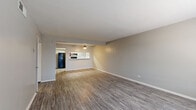 This single-floor residence offers a clean, functional layout with a neutral color palette and modern finishes throughout. The open living area is anchored by durable wood-look plank flooring and flows seamlessly toward the kitchen, which is accessible via a pass-through counter. The kitchen is well-equipped with white cabinetry, white quartz-style countertops, a classic subway tile backsplash, a stainless steel sink, and black appliances including a gas range, over-range exhaust hood, and a full-size refrigerator. A ceiling fan with a pendant-style light fixture adds both function and character to this shared living and dining space. The bedrooms feature plush wall-to-wall carpet, ceiling fans, and windows fitted with blinds that allow for natural light and privacy. Each bedroom offers a comfortable, well-proportioned retreat. The bathroom is notably spacious, presenting an elongated dual-sink vanity with light gray cabinetry, white countertops, and large mirrors illuminated by a Hollywood-style light bar. Wood-look flooring continues into the bathroom, maintaining a cohesive aesthetic. Throughout the residence, clean white trim and neutral gray walls create a bright, move-in-ready environment.