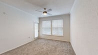 Located at 9345 Blue House Rd in North Charleston, SC, this single-floor, one-bedroom, one-bathroom residence offers a practical and comfortable layout. The living room is bright and welcoming, featuring plush carpeting, a ceiling fan with light kit, and multiple windows dressed with horizontal blinds that allow natural light to filter through. A door from the living area provides convenient outdoor access. The bedroom is generously proportioned, with soft carpeting underfoot, a ceiling fan, and a large window overlooking greenery. Two closets provide ample storage, including a spacious walk-in closet outfitted with wire shelving systems on multiple walls, offering excellent organization capacity. The bathroom is well-appointed, featuring a tub/shower combination with classic white tiling accented by a decorative mosaic border, a vanity with granite countertops and white cabinetry, and wood-look flooring that adds warmth. Crown molding details are visible throughout portions of the home, lending a refined touch. Neutral wall tones and consistent flooring choices create a cohesive, clean aesthetic throughout the residence, making it a functional and move-in ready space in North Charleston.