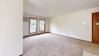 Located at 7705 Carrington Dr in Madison, WI, this single-floor, 2-bedroom, 1-bathroom unit offers a practical and comfortable layout across a well-utilized footprint. The living room serves as the heart of the home, featuring a tile-surround fireplace, plush carpeting, a ceiling fan, and a sliding door that fills the space with natural light and offers outdoor views. Warm-toned wood trim and baseboards provide consistent character throughout. The galley-style kitchen is efficiently designed with rich oak cabinetry, granite-look countertops, tile flooring, black appliances, and a window that brings in additional natural light. Both bedrooms are carpeted and bright, each equipped with windows framing green outdoor scenery and baseboard heating. The primary bedroom is generously sized and includes access to a well-appointed walk-in closet with built-in shelving and hanging rods. The full bathroom features tile flooring, an oak vanity with a granite-look countertop, and a large mirror. A dedicated laundry room houses a full-size washer and dryer alongside wire shelving for added storage. This thoughtfully laid-out unit combines functionality with comfortable living in a convenient Madison location.
