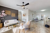 Located in Cocoa Beach, Florida, this well-appointed 2-bedroom, 2-bathroom unit offers a thoughtfully designed single-floor layout that blends modern style with comfortable coastal living. The open-concept living and dining area is a standout, featuring elegant marble-look tile flooring, crown molding, and a dramatic dark shiplap accent wall adorned with geometric gold artwork. A ceiling fan with integrated lighting anchors the space, while large windows allow natural light to fill the room. The kitchen is well-equipped with white raised-panel cabinetry, dark granite countertops, stainless steel appliances, and ample storage throughout. The primary bedroom is generously sized, featuring crown molding, a chandelier, and natural light from a large window. The second bedroom offers a bright, serene retreat with a closet and clean finishes. Both bathrooms are tastefully updated, with one showcasing a spacious walk-in glass-enclosed shower with floor-to-ceiling tile surround. A dedicated laundry room houses a full-size washer and dryer with overhead cabinetry for additional storage. Consistent marble-look tile flooring flows throughout the entire unit, tying all rooms together in a cohesive, polished aesthetic ideal for the Florida lifestyle.