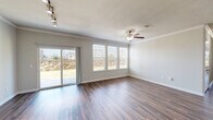 This well-designed single-story home offers four bedrooms and four bathrooms across a comfortable and functional floor plan. Rich, dark hardwood-style flooring flows consistently throughout the home, complemented by crown molding and neutral gray walls that create a clean, cohesive aesthetic.

The open-concept living, dining, and kitchen area serves as the heart of the home. The living space features a ceiling fan, track lighting, and a sliding glass door flanked by large windows that flood the room with natural light and provide views of the outdoor surroundings. An elegant arched doorway adds a refined architectural touch to the space.

The kitchen is outfitted with rich dark cabinetry, granite countertops, a tile backsplash, and stainless steel appliances including a refrigerator, range, and microwave. A kitchen island provides additional prep and dining space.

The primary bedroom is generously sized, featuring a ceiling fan, natural light, and access to a walk-in closet with built-in shelving. Additional bedrooms are well-proportioned, each with ceiling fans and ample closet space.

The bathrooms are thoughtfully finished with dark wood vanities, granite countertops, and tiled tub-and-shower combinations. The home also includes a dedicated entrance, a hallway, and five closets for abundant storage throughout.