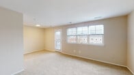 Located at 1628 N Hilton St in Baltimore, MD, this single-floor unit offers a clean, straightforward layout designed for comfortable everyday living. The main living area is generously proportioned, finished with neutral-toned carpet and warm beige walls that create a bright, welcoming atmosphere. A bank of windows along one wall, fitted with blinds, allows ample natural light to fill the space while providing views of the surrounding neighborhood. A glass-panel door leads directly to a private balcony, extending the living area outdoors.

The bedrooms continue the same neutral carpet and beige color palette, each featuring windows that bring in natural light and views of the adjacent brick residential buildings. One bedroom includes two closet doors, offering practical storage.

The kitchen is efficiently arranged in a galley-style configuration, featuring dark wood cabinetry with brushed hardware, light stone-toned countertops, a stainless steel sink, and black appliances including a refrigerator, range, microwave, and dishwasher. Light hardwood-style flooring grounds the kitchen space.

The bathroom is finished with white tile surrounding a full soaking tub and shower combination, complemented by a vanity with a light countertop, a large mirror, and a window providing natural ventilation and light.