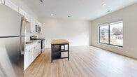 This 550 square foot apartment, located at address I2-201, offers a well-designed living space on a single floor. The unit features one bedroom, measuring 120 square feet, which includes a large window providing natural light and views of the surrounding area. The modern kitchen is equipped with stainless steel appliances, white cabinetry, and a convenient island with a wooden top, perfect for meal preparation or casual dining. The open-concept layout seamlessly integrates the kitchen with the living area, enhancing the sense of space. The bathroom boasts a clean, contemporary design with a white vanity, ample storage, and a combination tub-shower. Light-colored walls throughout the apartment create a bright, airy atmosphere, while the mix of carpeting in the bedroom and wood-look flooring in the main living areas adds warmth and texture. Recessed lighting and large windows contribute to the overall luminosity of the space. Despite its compact size, the apartment includes a closet for additional storage. The efficient layout and modern finishes make this apartment an ideal choice for those seeking a comfortable, low-maintenance living space in a developing area.