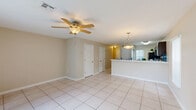 Located at 183 Tara Oaks Cir in Lady Lake, Florida, this two-story home offers a practical and comfortable layout spread across two floors. The main level features light-colored tile flooring throughout, a well-appointed kitchen with dark cabinetry, light countertops, black appliances including a range, refrigerator, and dishwasher, plus a peninsula with a double sink. Natural light filters in through vertical blinds. The dining area flows naturally from the kitchen, and the main living area opens to the backyard through a sliding glass door, offering pleasant outdoor views. A staircase connects the main level to the upper floor, where both bedrooms are situated. Each bedroom is carpeted and equipped with a ceiling fan, creating a comfortable atmosphere. The spacious primary bedroom offers generous proportions and dedicated closet space. The second bedroom also benefits from natural light through a window with vertical blinds. The shared full bathroom includes a tub/shower combination, a vanity with a large mirror, and a window that brings in natural light, all finished in clean white tiling. Two closets provide ample storage throughout the home. Ceiling fans are present in every room, a practical feature well-suited to the Florida climate.