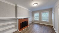 This single-floor, three-bedroom, one-bathroom home in Milwaukee, Wisconsin offers a blend of classic character and functional living. The living room serves as the centerpiece of the home, showcasing a striking brick fireplace with a white mantel and built-in shelving alongside it, adding both warmth and architectural interest. Crown molding, a textured accent wall, and a wainscoting detail further enhance the room's classic character, while a pair of windows invites ample natural light and views of the surrounding greenery. Hardwood flooring runs throughout the home, lending a cohesive, timeless appeal. The kitchen is well-appointed with rich, dark cabinetry, clean white countertops, a stainless steel sink, and a gas range, providing a practical and efficient cooking space. Each of the three bedrooms features hardwood floors and neutral walls. Two of the bedrooms include closets for added storage, and windows provide natural light to each room. One bedroom features paneled wall detailing, adding a distinctive touch. The full bathroom is neatly finished with a tiled tub-and-shower surround, a white vanity, and wood-look flooring, creating a clean and functional space.