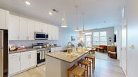 Located at 509 W Rich St in Columbus, OH, this well-appointed one-bedroom, one-bathroom residence offers a thoughtfully designed single-floor layout that maximizes every square foot of its compact footprint. The open-concept kitchen and living area serves as the heart of the home, anchored by a generous center island with a built-in sink, pendant lighting, and seating — perfect for both casual dining and entertaining. The kitchen is outfitted with crisp white cabinetry extending to the ceiling, dark countertops, and a full suite of stainless steel appliances, including a refrigerator, range, and over-the-range microwave. Light wood-style flooring runs throughout, lending warmth and visual continuity. The living room is bright and airy, with large windows and a glass door opening to a private balcony, filling the space with natural light. The bedroom offers a comfortable retreat with multiple windows, neutral tones, and plush carpeting. The bathroom is clean and modern, featuring white cabinetry, a single vanity with a wide mirror, and a frameless glass walk-in shower. A dedicated closet provides practical storage. The overall aesthetic is contemporary and welcoming, with a neutral palette throughout.