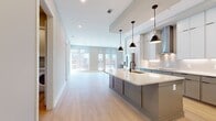 This contemporary apartment offers a spacious 1230 square feet of living area, thoughtfully designed with an open floor plan. The heart of the home is a combined kitchen and living room, perfect for entertaining or relaxing. Large windows dominate the space, flooding the interior with natural light and offering views of the surrounding urban landscape.

The apartment boasts two bedrooms, including a primary bedroom of 200 square feet, providing ample space for comfort and privacy. Two full bathrooms add convenience for residents and guests alike. The home also features two closets for storage, a separate laundry room for added functionality, and a hallway connecting the various spaces.

The interior design is characterized by a neutral color palette, with light gray walls complementing the pale wood-toned flooring. This creates a serene and modern atmosphere throughout. Recessed lighting in the ceiling adds to the contemporary feel while providing adjustable illumination options.

Window treatments, likely roller shades, offer privacy and light control without detracting from the clean lines of the space. The overall ambiance is one of urban sophistication, ideal for those seeking a turnkey, low-maintenance lifestyle in a bright, airy environment.
