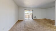 Located at 1942 Deerpark Dr in Fullerton, California, this efficiently designed single-floor unit offers a well-organized layout comprising a living area, kitchenette, and a full bathroom. The living area features wall-to-wall carpeting in warm neutral tones, crisp white walls, and a sliding glass door fitted with vertical blinds that opens to an outdoor patio, filling the space with natural light and providing a pleasant outdoor connection. A wall-mounted air conditioning unit serves the living area for year-round comfort. The kitchen is separated from the living space by a partial wall divider and is equipped with a white electric range and refrigerator, complemented by white cabinetry and wood-look flooring that extends into the adjoining areas. A closet off the living area provides dedicated storage. The bathroom is clean and functional, featuring a combined shower and tub with a curved surround, a toilet with a grab bar, and wood-look vinyl flooring that adds warmth to the space. Throughout the unit, the consistent white palette and clean finishes create a bright, cohesive atmosphere. The layout makes efficient use of every square foot, offering a practical and comfortable living environment in a convenient Fullerton location.