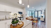 Located at 555 Linger Longer Drive on Johns Island, SC, this one-bedroom, one-bathroom residence offers a well-appointed, efficiently designed floor plan that maximizes every square foot. The open-concept kitchen flows seamlessly into the living and dining areas, creating a cohesive and functional living space. The kitchen is equipped with stainless steel appliances, including a refrigerator, microwave, and dishwasher, and features crisp white cabinetry, a granite-topped center island with pendant lighting overhead, and light wood-style flooring that extends throughout the main living areas. The living room is bright and welcoming, with multiple windows dressed in plantation shutters that invite natural light, a ceiling fan, and French doors that open to a private outdoor balcony with wooded views. The bedroom is a calm retreat with carpet flooring, ceiling fan, and windows offering additional natural light. The full bathroom is finished with granite countertops, white cabinetry, light wood-style tile flooring, and a tub-shower combination with subway tile surround. Neutral tones and clean finishes throughout give the space a fresh, modern coastal character well-suited to the Johns Island setting.
