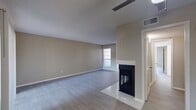 This recently renovated home boasts a spacious layout with seamless flow between living areas. The main living space features a striking fireplace as its focal point, complemented by sleek gray flooring. The kitchen showcases white cabinetry, stainless steel appliances, and a subway tile backsplash. Bedrooms offer ceiling fans and closet space, while the bathroom features a modern vanity and tiled floors. Large windows and sliding glass doors provide abundant natural light, enhancing the airy feel of the home. The neutral color scheme and contemporary fixtures create a clean, sophisticated ambiance throughout the property.