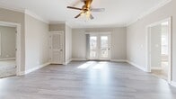 Located at 119 Cornerstone St in Lynchburg, Virginia, this well-appointed single-story home offers three bedrooms, two bathrooms, and a thoughtfully designed layout. The open-concept kitchen is a standout feature, showcasing rich dark wood cabinetry, granite countertops, a subway tile backsplash, a central island with pendant lighting, and a full suite of stainless steel appliances. The kitchen flows seamlessly into the living area, which is finished with light hardwood-style flooring, crown molding, and a ceiling fan. French doors in the living room invite natural light and provide access to outdoor views. The primary bedroom is generously sized, featuring plush carpeting, a ceiling fan, and a dedicated walk-in closet. The two additional bedrooms are also carpeted with ceiling fans, offering comfortable and functional spaces. Both bathrooms are finished consistently, each featuring a dark wood vanity with a granite-topped sink, tile flooring, and a full bathtub with shower. A dedicated laundry room houses a full-size washer and dryer. Crown molding and neutral tones throughout lend a cohesive, clean aesthetic to the entire home.