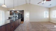 Located at 711 E Cloud Ave in Andover, Kansas, this well-appointed 3-bedroom, 2-bathroom home offers a thoughtfully designed single-floor layout that maximizes both comfort and functionality. The heart of the home is a striking open-concept living and dining area anchored by dramatic vaulted ceilings with exposed beams and a ceiling fan, creating a bright and airy atmosphere. Soft carpeting flows through the living space, while warm hardwood-style flooring runs through the kitchen and utility areas. The kitchen is outfitted with rich dark cabinetry, dark granite countertops, a tile mosaic backsplash, pendant lighting, and black appliances including a range, microwave, and refrigerator. A sliding glass door opens to an outdoor deck, bringing in natural light and views of the surrounding neighborhood. The three bedrooms are carpeted and well-lit, each featuring windows with blinds and ceiling fans. The primary bedroom offers a comfortable, private retreat. Both bathrooms are clean and functional, with one featuring a full tub-shower combination. A dedicated laundry room accommodates a full-size washer and dryer side by side. A carpeted staircase with a handrail provides access to additional levels. This home blends practical living with modern design details throughout.