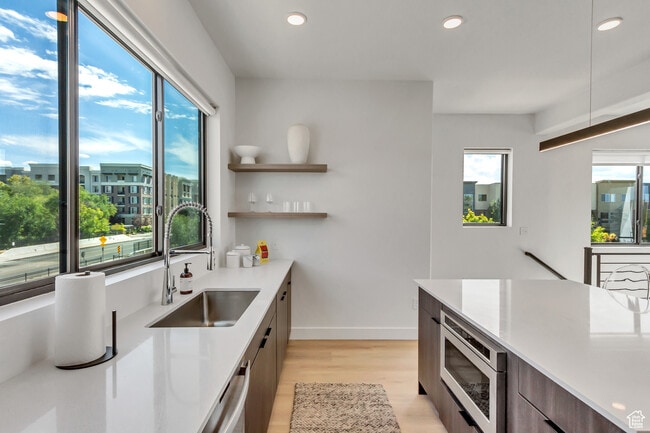 Kitchen featuring modern cabinets, open floor plan, a center island, light wood finished floors, and - 44 W Iko Ave