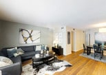 This single-floor residence at Evergreen Terrace at Hickory Valley offers a thoughtfully designed layout that balances comfort and modern style. The open living and dining area is anchored by rich hardwood-style flooring that flows seamlessly throughout the common spaces, creating a warm and cohesive atmosphere. The living room features neutral-toned walls accented with a deep charcoal sectional sofa and a striking cowhide area rug, while the adjacent dining space accommodates a round table beneath a pendant light fixture.

The galley-style kitchen is both functional and well-appointed, featuring gray cabinetry with sleek hardware, a neutral mosaic tile backsplash, light countertops, a double stainless steel sink, and a full suite of appliances including a stainless steel refrigerator, electric range, and built-in microwave.

The bedrooms offer a calm retreat, with plush carpeting, natural light from well-dressed windows, and soft, neutral color palettes. Each room provides a comfortable and restful environment.

The bathroom is clean and practical, offering a wide vanity with a large framed mirror, modern light fixtures, hardwood-style flooring, and a shower-tub combination — providing all the essential amenities in a well-maintained space.