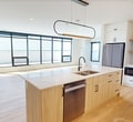 This contemporary residence at 112 St James Street, London ON, offers 2130 square feet of meticulously designed living space on a single floor. The home boasts 4 bedrooms, including a spacious 250 sq ft primary suite, and 5 bathrooms, ensuring comfort and privacy for all occupants. The open-concept layout seamlessly integrates the kitchen and living areas, creating a fluid space ideal for both everyday living and entertaining.

The kitchen is a standout feature, showcasing sleek white cabinetry, ample storage, and high-end appliances. Light-colored quartz countertops complement the modern aesthetic, while under-cabinet lighting adds both functionality and ambiance. The living areas are graced with warm wood flooring, creating a cohesive flow throughout the home.

Large windows are a prominent feature, flooding the rooms with natural light and offering picturesque views of the surroundings. The bathrooms are elegantly appointed, with one featuring a stylish combination of white tile work and contrasting dark fixtures. A dedicated laundry room with stacked, modern appliances adds convenience to daily life.

The property's design emphasizes clean lines, neutral tones, and a minimalist approach, creating a sense of spaciousness and serenity. With its thoughtful layout and high-quality finishes, this home represents the epitome of contemporary urban living.
