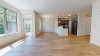 This two-story residence is designed with a clean, contemporary aesthetic that balances functionality and comfort throughout. The main level centers on an open-concept living and dining area finished with light hardwood flooring that extends seamlessly into the kitchen. Large windows and a glass-paneled exterior door flood the living space with natural light while offering views of surrounding greenery.

The kitchen is well-equipped with dark espresso cabinetry, stainless steel appliances including a range, microwave, refrigerator, and dishwasher, complemented by light countertops and a peninsula island ideal for casual dining or food preparation. Pendant lighting adds a modern touch overhead.

A half bathroom on the main level features a rich wood vanity with granite countertop and a large mirror. The upper floor hosts the bedrooms, each carpeted and generously sized with windows framing tree-lined outdoor views. The primary bedroom includes a walk-in closet outfitted with wire shelving systems for organized storage. A full bathroom with a tub-shower combination and white tile surround serves the upper level. A dedicated in-unit laundry room with a full-size washer and dryer adds everyday convenience.