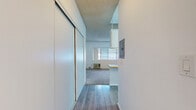 Located at 10625 Petit Ave in Granada Hills, Los Angeles, this single-floor studio offers a well-organized and functional layout. The living area is carpeted and bathed in natural light from a large picture window, which provides views of the surrounding neighborhood and allows ample daylight to fill the space. A wall-mounted air conditioning unit ensures year-round comfort.

The kitchen is open to the living area via a pass-through counter with a warm wood-tone surface, making the space feel connected and sociable. Upper cabinetry in neutral tones provides practical storage, and a white range with overhead ventilation completes the cooking area.

An entry corridor features smooth hardwood-style flooring and large sliding closet doors, offering generous storage before opening into the main living space. The textured ceiling runs throughout, adding a subtle architectural character consistent with classic Los Angeles residential construction.

The bathroom is clean and simply appointed, with a full-size tub and shower combo fitted with chrome fixtures, a toilet, vanity, and wood-style flooring that ties in with the entryway. White walls and bright lighting lend the bathroom a crisp, clean aesthetic.

Overall, the space presents a bright, neutral palette with a practical, no-frills design well-suited for efficient single-occupant living in the San Fernando Valley.