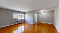 Located at 1420 W Abingdon Drive in Alexandria, Virginia, this efficiently designed single-floor unit offers a practical and comfortable layout comprising a living room, kitchen, bathroom, closet, and hallway. The living room serves as the heart of the space, showcasing beautifully polished hardwood floors that run throughout and reflect natural light streaming in from a multi-pane window. Neutral gray walls create a calm, versatile backdrop, while a ceiling fan provides year-round comfort. A wall-mounted radiator and window AC unit ensure climate control in every season. The entry hallway leads seamlessly into the living area, maintaining an open and connected flow. The kitchen is well-appointed with white cabinetry, dark laminate countertops, a stainless steel sink, and a white gas range. A window above the counter brings in natural light, making the space feel bright and functional. The bathroom features a clean, all-white tub and shower surround with crisp paneled doors, offering a simple and tidy design. A dedicated closet provides practical storage. Throughout the unit, white baseboards and clean finishes contribute to a tidy, move-in-ready aesthetic.