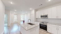 Located at 2652 S Main St NW in Kennesaw, GA, this thoughtfully designed single-floor, one-bedroom, one-bathroom residence offers a clean, contemporary aesthetic throughout. The open-concept kitchen serves as the heart of the home, showcasing a granite-topped center island with an undermount sink, crisp white shaker cabinetry, a tile backsplash, and a full suite of stainless steel appliances including a refrigerator with ice maker, electric range, and over-the-range microwave. Light wood-style flooring flows seamlessly through the kitchen and living areas, lending warmth and continuity to the space. The living area benefits from natural light provided by windows fitted with blinds and direct access via a glass-panel door. The bedroom is a calm retreat featuring plush carpeting, a ceiling fan, and a window with outdoor views. A walk-in closet with wire shelving provides ample storage. The full bathroom is well-appointed with a double granite-topped vanity, white cabinetry, a large wall mirror, and a tiled tub-shower combination. A stacked washer and dryer unit is conveniently integrated within the bathroom area. Recessed lighting throughout enhances the bright, modern ambiance of this well-appointed Kennesaw residence.