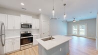 Located at 111 Teal Cir in Little River, SC, this well-designed single-story home offers a thoughtful layout across one bedroom and two full bathrooms. The open-concept kitchen and living area serves as the heart of the home, anchored by a central island with a quartz countertop, undermount sink, and stylish pendant lighting overhead. White shaker cabinetry, a subway tile backsplash, and a full suite of stainless steel appliances — including a range, microwave, and refrigerator — lend a clean, contemporary feel. Light wood flooring flows throughout the main living areas, complementing the soft, neutral wall tones and recessed lighting. The living room benefits from natural light and an outdoor-facing door, creating a bright and airy atmosphere with ceiling fan comfort. The carpeted bedroom offers a peaceful retreat with a ceiling fan, natural light from a window, and access to a spacious walk-in closet with wire shelving. The bathrooms are finished with white vanities, quartz countertops, and brushed hardware. A dedicated laundry room houses a full-size washer and dryer, adding convenience. The overall design is modern, cohesive, and move-in ready.