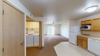 Located at 1050 Flammang Dr in Waterloo, Iowa, this single-floor 1-bedroom, 1-bathroom unit offers a practical and comfortable layout designed for efficient living. The open-concept kitchen and living room area forms the heart of the unit, with the kitchen featuring warm oak cabinetry, ample counter space, and white appliances including a refrigerator, electric range, dishwasher, and microwave. Light-colored vinyl flooring in the kitchen transitions seamlessly into carpeted living areas. The spacious living room is brightened by a sliding glass door that brings in natural light and provides outdoor access, complemented by a ceiling fan overhead. The generously sized bedroom also features plush carpet, a ceiling fan with light fixture, and a window overlooking the outdoors, creating a bright and restful retreat. Three closets throughout the unit provide excellent storage capacity. A dedicated laundry closet with in-unit washer and dryer hookups adds everyday convenience. The full bathroom includes a walk-in shower with grab bar, a wood-toned vanity with countertop sink, and a large mirror. Neutral tones and clean finishes throughout give the space a welcoming and functional character.