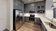 Located at 4124 Providence Road in Charlotte, NC, this single-floor unit delivers a well-appointed, contemporary living environment with consistent design elements throughout. The open-concept living and dining area is anchored by warm wood-look plank flooring, recessed lighting, and bold dark crown molding that frames the crisp white walls. A set of glass-paneled French doors floods the space with natural light and opens directly onto a private balcony, providing views of the surrounding community.

The kitchen is a standout feature, outfitted with floor-to-ceiling gray shaker-style cabinetry, white quartz countertops, a classic subway tile backsplash, and a full suite of stainless steel appliances including a French door refrigerator, electric range with over-the-range microwave, and dishwasher. A peninsula with pendant lighting serves as both a prep area and casual dining space, connecting seamlessly to the main living area.

The bedrooms feature plush carpeting, large windows with horizontal blinds, and ceiling fans for added comfort. The bathrooms are finished with striking marble-look porcelain tile flooring and wall surrounds, gray cabinetry with white countertops, glass-enclosed showers, and soaking tubs, conveying a refined, spa-like aesthetic throughout.