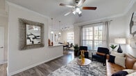 Located in the Briar Forest area of Houston, TX, this well-appointed one-bedroom, two-bathroom residence offers a thoughtfully designed single-floor layout. The open living and dining area forms the heart of the home, featuring rich hardwood-style flooring, crown molding, and a ceiling fan that add a polished, classic character. Large windows with plantation-style blinds bathe the space in natural light while offering views of the surrounding greenery. The galley-style kitchen is well-equipped with dark espresso cabinetry, granite-style countertops, stainless steel appliances, and a deep undermount sink — a functional and stylish space for cooking. A dedicated dining area sits just off the kitchen and living room, comfortably accommodating a full dining set. A built-in office nook with a granite desktop and floating shelves provides a compact yet efficient workspace. The spacious bedroom features plush carpeting, a ceiling fan, and direct access to a generous walk-in closet with built-in shelving. The primary bathroom offers a long dual-sink vanity with dark cabinetry, granite countertops, large-format tile flooring, and a full soaking tub. A second bathroom and a private patio complete this comfortable and versatile residence.