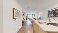 This thoughtfully designed 2-bedroom, 3-bathroom residence at 95 Maple St in Stoneham, MA offers a seamless blend of modern finishes and functional living. The open-concept kitchen and living area serves as the heart of the home, featuring light wood cabinetry, a white quartz waterfall island, stainless steel appliances including a range, microwave, and refrigerator, and a tile backsplash. Hardwood-style flooring flows throughout, tying each space together cohesively. The living room is bathed in natural light from large sliding glass doors that open to a private balcony with outdoor views. Both bedrooms are comfortably sized, with the primary bedroom offering a ceiling fan, large windows, and direct access to a well-appointed en-suite bathroom. The bathrooms are finished with marble-inspired tile, frameless glass shower enclosures, brushed gold hardware, and floating wood vanities with white quartz countertops. Six closets, including spacious walk-in closets outfitted with wire shelving systems, provide generous storage throughout. A dedicated laundry area adds further convenience. The interior design palette of crisp whites, warm wood tones, and soft neutrals creates a bright, welcoming ambiance throughout the entire residence.
