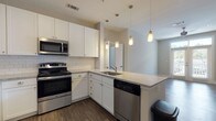 Located on Davis Circle NW in Atlanta, Georgia, this single-floor residence offers a thoughtfully designed layout with modern finishes throughout. The kitchen is a standout feature, showcasing white shaker-style cabinetry, granite-look countertops, a classic white subway tile backsplash, and a full suite of stainless steel appliances including a refrigerator, range, microwave, and dishwasher. An peninsula with a built-in sink and pendant lighting above adds both functionality and style, while wood-look plank flooring grounds the space with warmth and durability. The open living area flows naturally from the kitchen, featuring the same wood-look flooring and a ceiling fan overhead, creating a bright and airy atmosphere. Bedrooms are finished with plush wall-to-wall carpeting and feature windows with blinds that bring in natural light. The unit includes two bathrooms: one with a soaking tub and tiled surround, and another featuring a glass-enclosed walk-in shower — both appointed with white vanities, granite-look countertops, and matching wood-look flooring. Neutral wall tones throughout lend the space a clean, cohesive aesthetic well-suited for a variety of interior styles.
