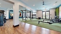 Located at 4222 White Birch Avenue in Smyrna, Tennessee, this modern fitness center offers a thoughtfully designed, single-level space that accommodates a comprehensive range of workout disciplines. The open floor plan combines rich hardwood flooring with dedicated green turf training zones, clearly delineating functional fitness areas from traditional strength training sections.

The facility is outfitted with an impressive array of equipment, including a power rack with barbells and weight plates, a full dumbbell rack, kettlebells, medicine balls, a rowing machine, battle ropes, and a heavy punching bag — providing options for strength, cardio, and functional training alike. A separate, glass-enclosed room houses additional cardio and weight machines, maximizing the use of the overall space.

Natural light streams in through large windows and glass garage-style doors, creating a bright and energizing atmosphere. Ceiling fans and recessed lighting maintain comfort throughout. Decorative touches, including a nature-themed mural and a living moss accent wall with scenic artwork, add a distinctive, motivating ambiance. Full-length mirrors amplify the sense of space and support proper form during workouts. The overall design strikes a balance between functionality and aesthetics, making this fitness center a standout amenity.