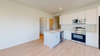 Located on the ninth floor at 8605 Cameron St in Silver Spring, MD, this thoughtfully designed two-bedroom, two-bathroom residence offers a clean, modern aesthetic throughout. Light hardwood flooring flows consistently across the single-level layout, complementing the crisp white walls and bright, airy atmosphere.

The kitchen serves as a functional centerpiece, featuring a central island with an integrated sink, stainless steel appliances including a range, microwave, refrigerator, and dishwasher, and a herringbone-patterned tile backsplash that adds a refined touch. White shaker cabinetry provides ample storage, while a large window and adjacent door offer access to a private balcony with views of the surrounding Silver Spring streetscape.

Both bedrooms are well-proportioned and bathed in natural light through large windows that frame elevated city views. The primary bedroom offers a comfortable footprint with access to its own dedicated bathroom. The hallway and closet provide practical connectivity and storage throughout the unit.

The two bathrooms are finished with matching dark herringbone floor tile and white subway tile walls. One bathroom features a glass-enclosed walk-in shower with a white vanity, while the second includes a full soaking tub with overhead shower. Together, they deliver a cohesive, contemporary design that is both stylish and functional.