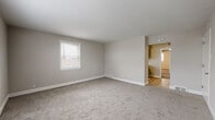 This single-floor residence offers a practical and comfortable layout designed for everyday living. The interior is finished with a consistent neutral color palette of soft greiges and warm whites, creating a calm and cohesive atmosphere throughout. Plush wall-to-wall carpeting covers the living and bedroom areas, while light hardwood-style flooring runs through the kitchen and connecting hallways.

The spacious living area features open sightlines and flows naturally into adjacent rooms, with a window providing an influx of natural light. Multiple bedrooms are spread throughout the floor plan, each outfitted with carpet flooring, ceiling fans with integrated lighting, and windows fitted with blinds. Several bedrooms include closets, offering practical storage solutions. One bedroom features dual windows that allow generous daylight from multiple directions.

The galley-style kitchen is a standout feature, showcasing rich dark wood cabinetry, granite countertops, a classic subway tile backsplash, and stainless steel appliances including a refrigerator, range, and dishwasher. Light wood-tone flooring and a window above the sink complete the space with a bright, functional feel.

The bathroom is finished in crisp all-white tile, featuring a soaking tub with tiled surround, a dark wood vanity, and a frosted privacy window. The overall design of this residence is clean, functional, and move-in ready.